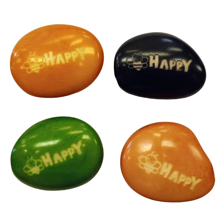 Four colorful tagua nut with 'bee HAPPY' engraved on them on a white background