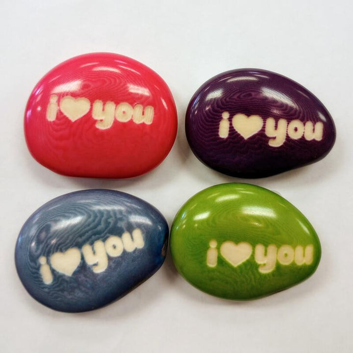 Four colorful tagua nuts with 'I ❤️ you' text on a white background