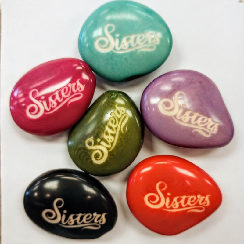 Colorful tagua nuts with 'Sisters' engraved on a white background