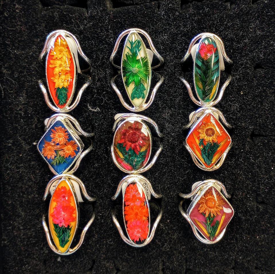 Silver rings with resin centers containing multicolor flowers of various shapes. 
