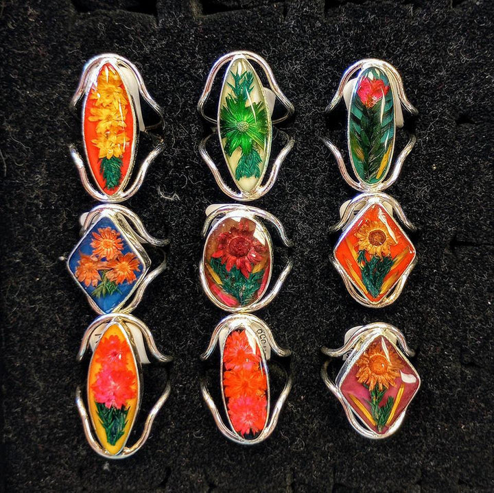Silver rings with resin centers containing multicolor flowers of various shapes. 