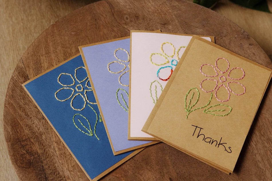 Four embroidered greeting cards with floral designs on a wooden surface