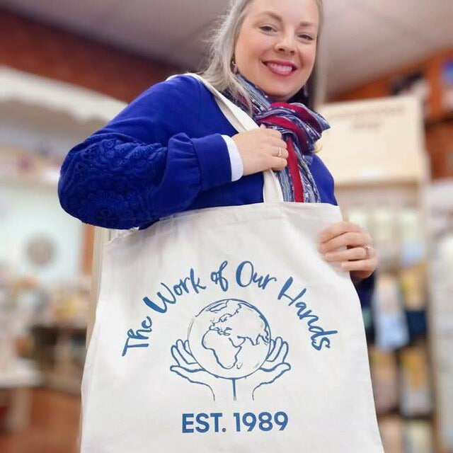 Person wearing a tote bag with 'The Work of Our Hands' logo and text.