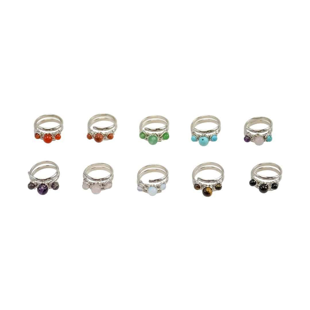 A collection of eight silver rings, each with a different semi-precious stone set in the center, displayed against a white background.