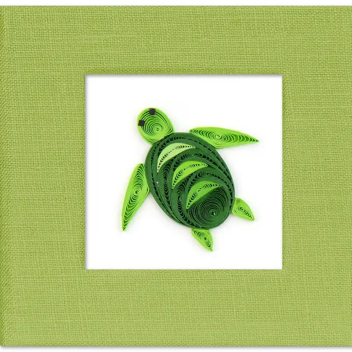 A handcrafted green sticky note cover with a quilled turtle design on the front, made of paper, displayed against a white background.