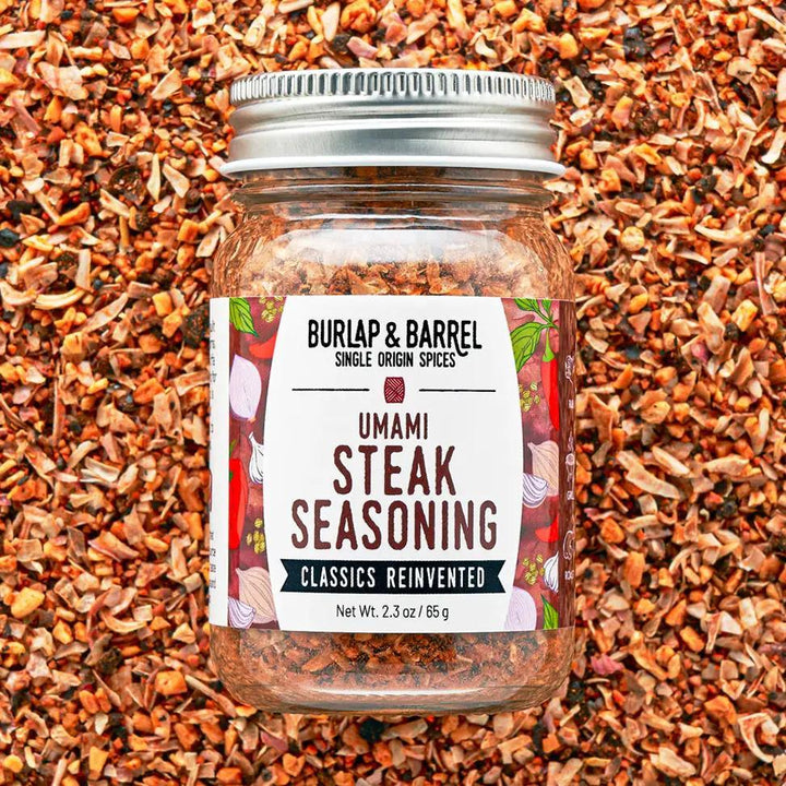 Jar of Burlap & Barrel Umami Steak Seasoning on a background of spices