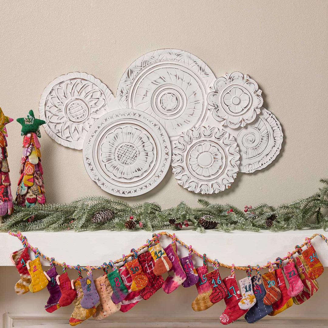 Decorative wall art with circular patterns above a mantel with stockings and garland.