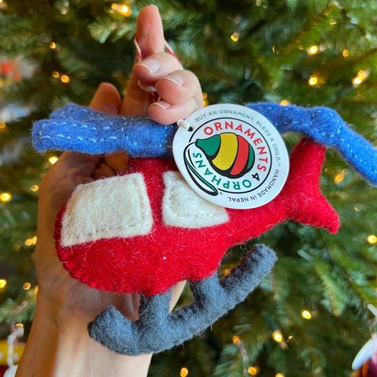 Handmade felt ornament in vehicle shape of red helicopter.