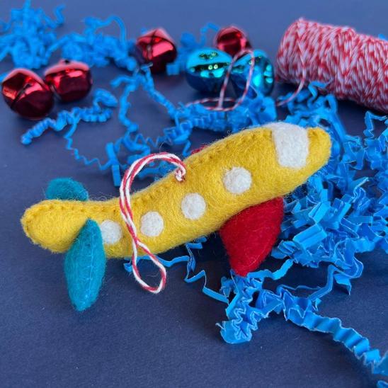 Handmade felt ornament in vehicle shape of yellow airplane.