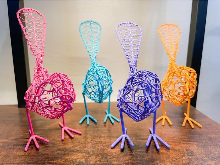 A group of colorful wire birds with outstretched wings in shades of pink, orange, blue, and purple.