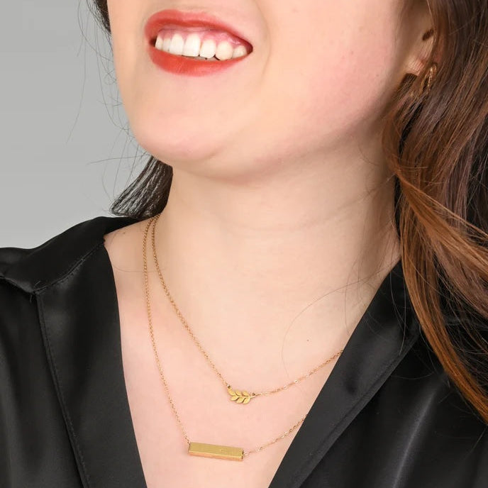 Close-up of a person wearing gold necklaces with a plain background