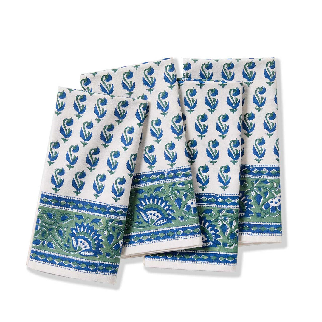 Set of three patterned cloth napkins with blue and green designs on a white background