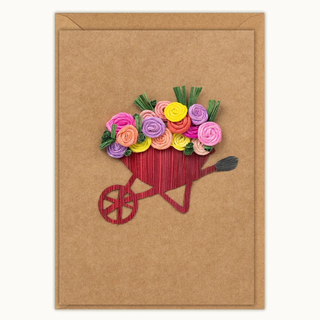 Card with a red wheelbarrow filled with colorful flowers on a brown background