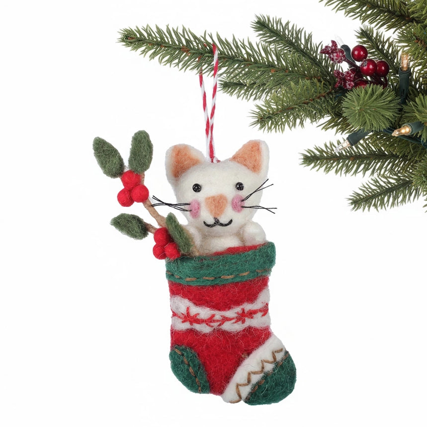 Cat in a red and green striped stocking Christmas ornament with holly leaves and berries on a white background.