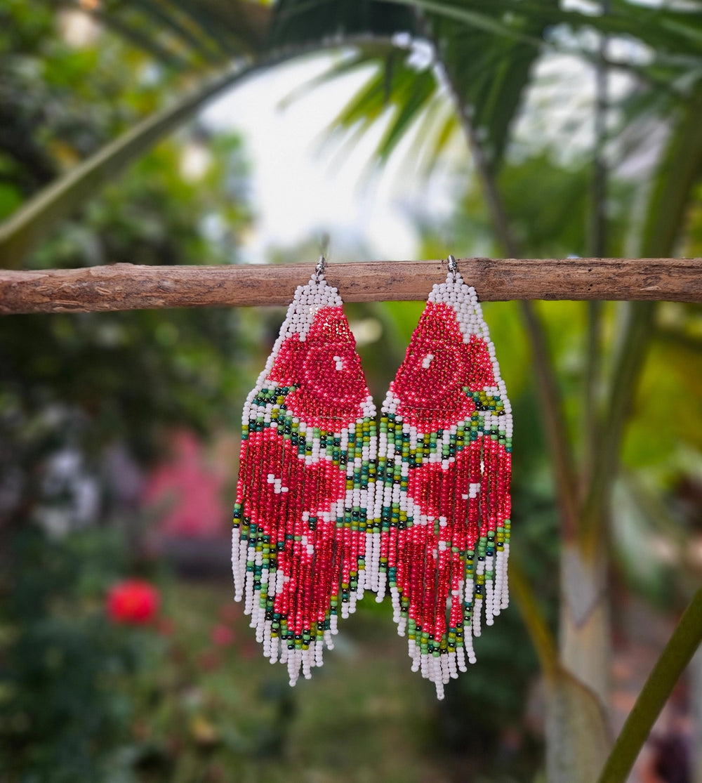 Beaded earrings hanging on a branch with a blurred natural background