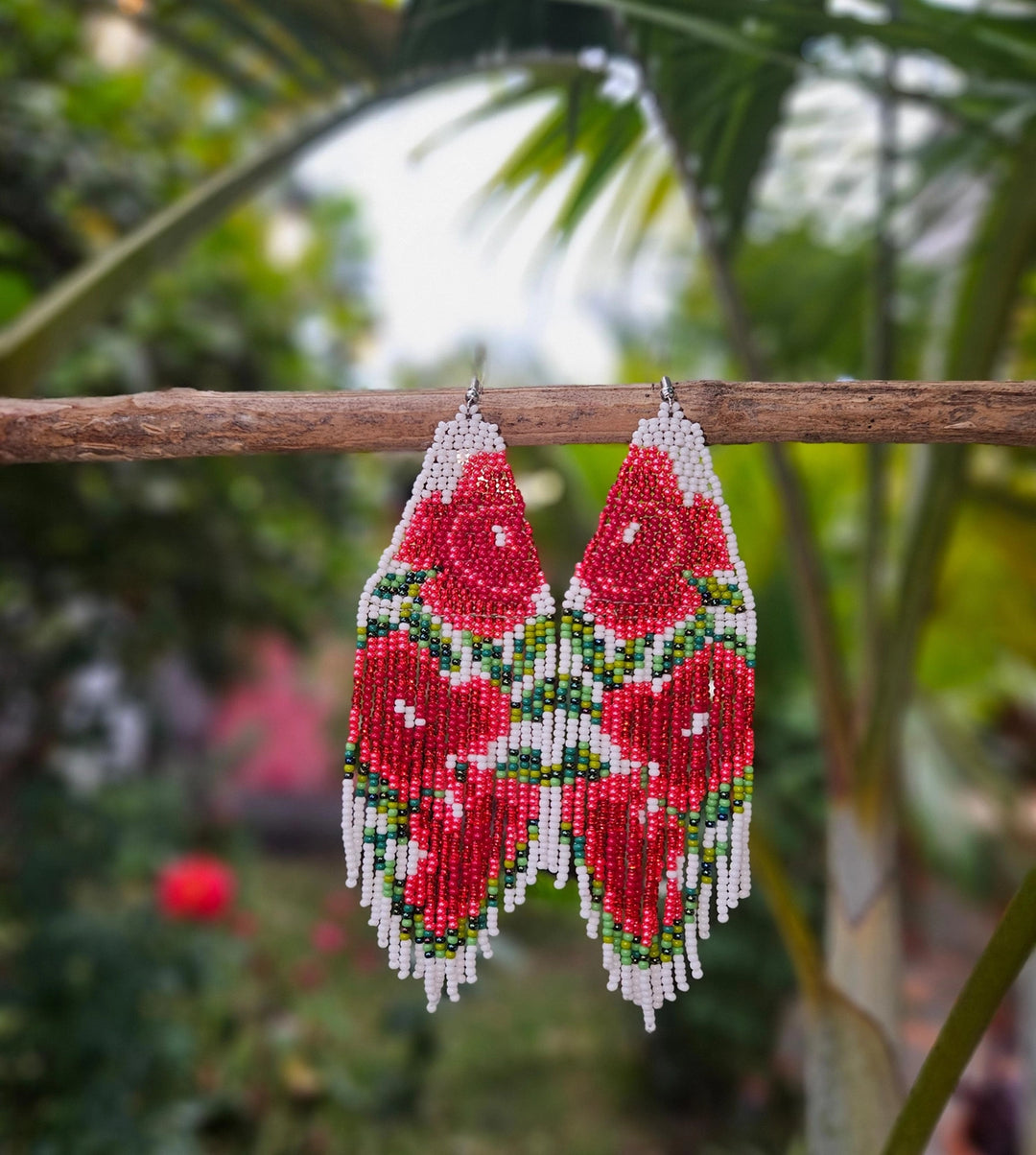 Beaded earrings hanging on a branch with a blurred natural background