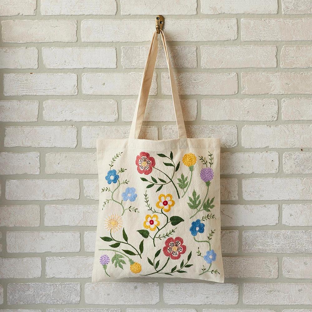Floral-patterned embroidered tote bag hanging on a brick wall