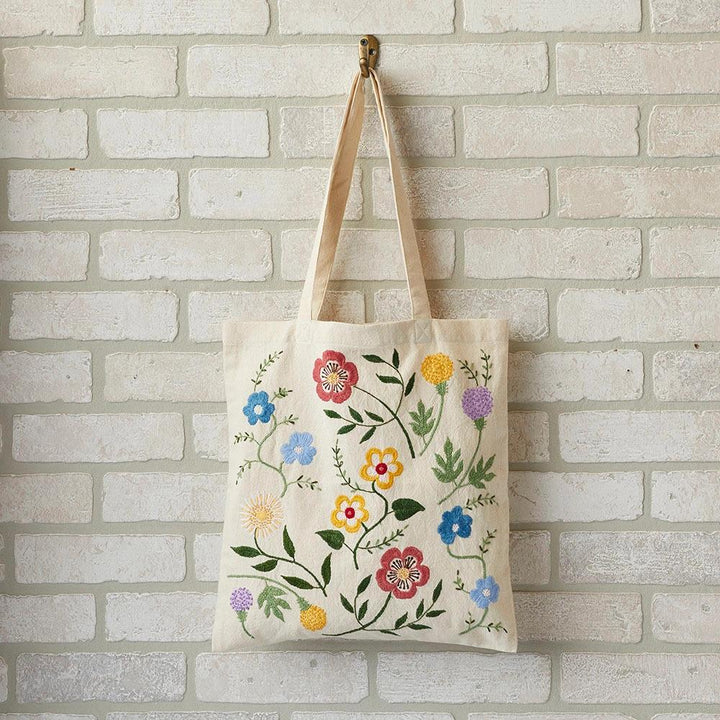 Floral-patterned embroidered tote bag hanging on a brick wall