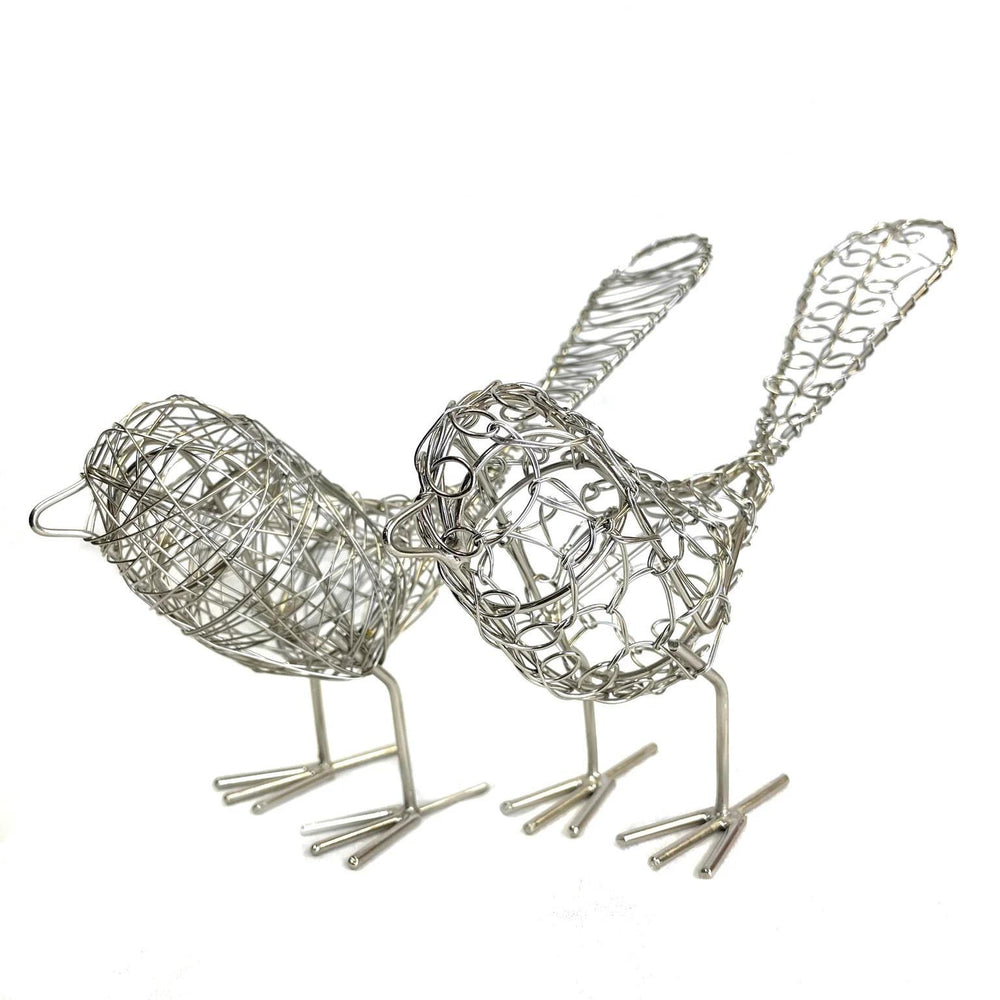 Silver colored hand made metal wire birds on a white background.