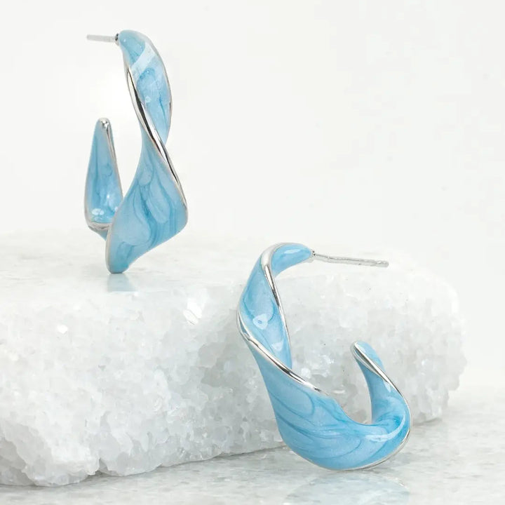 Blue marbled hoop earrings on a textured white surface