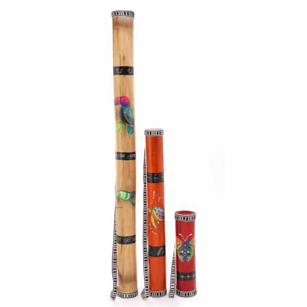 A collection of three rainsticks with straps, each with a different color and decorated with different bird and insect designs, standing upright against a white background.