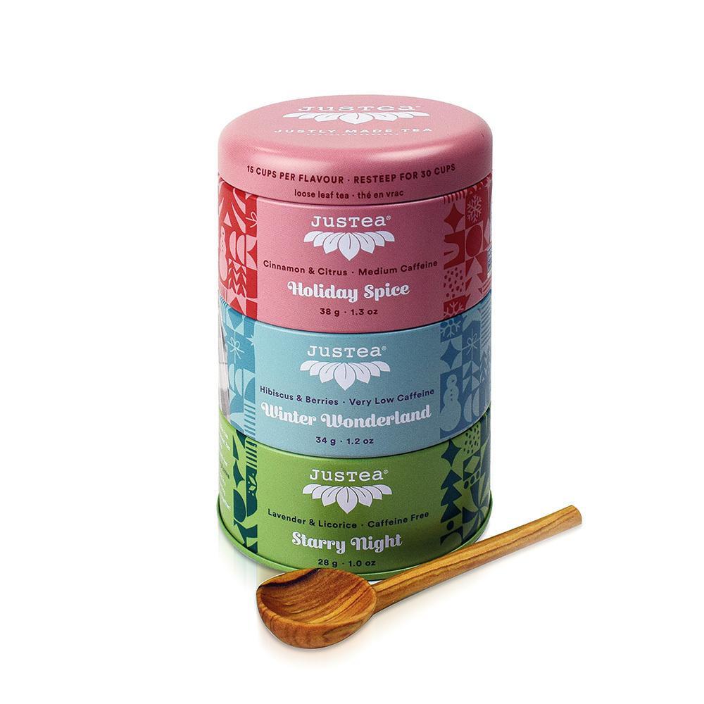 Justea holiday looseleaf tea trio on a white background with a carved wooden measuring spoon.