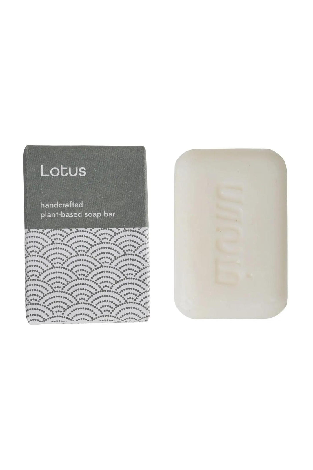 A bar of soap with a label that reads 'LOTUS Handcrafted Bar Soap' and a box with a geometric design in the background.