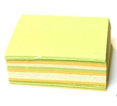 A stack of square-shaped, multicolored paper refills with a green top layer, indicative of the product's natural dyes and handmade origin.