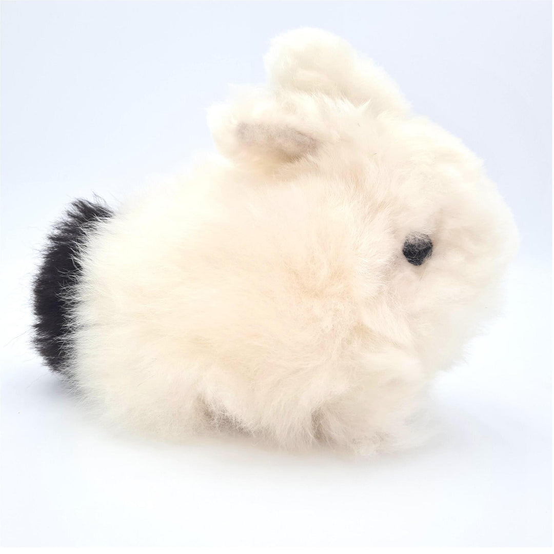 A plush toy resembling a bunny made from soft, fluffy alpaca fur in beige and black colors.