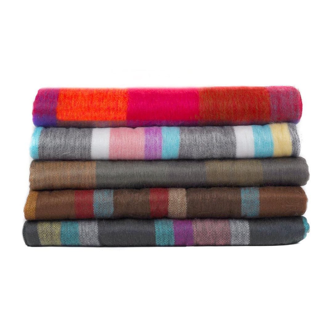 A stack of folded brushed acrylic blankets in various colors, including red, blue, gray, and multicolored patterns.