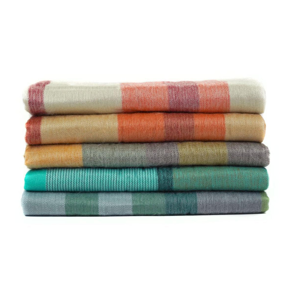 A stack of folded brushed acrylic blankets in various colors, including orange, green, yellow, and multicolored patterns.