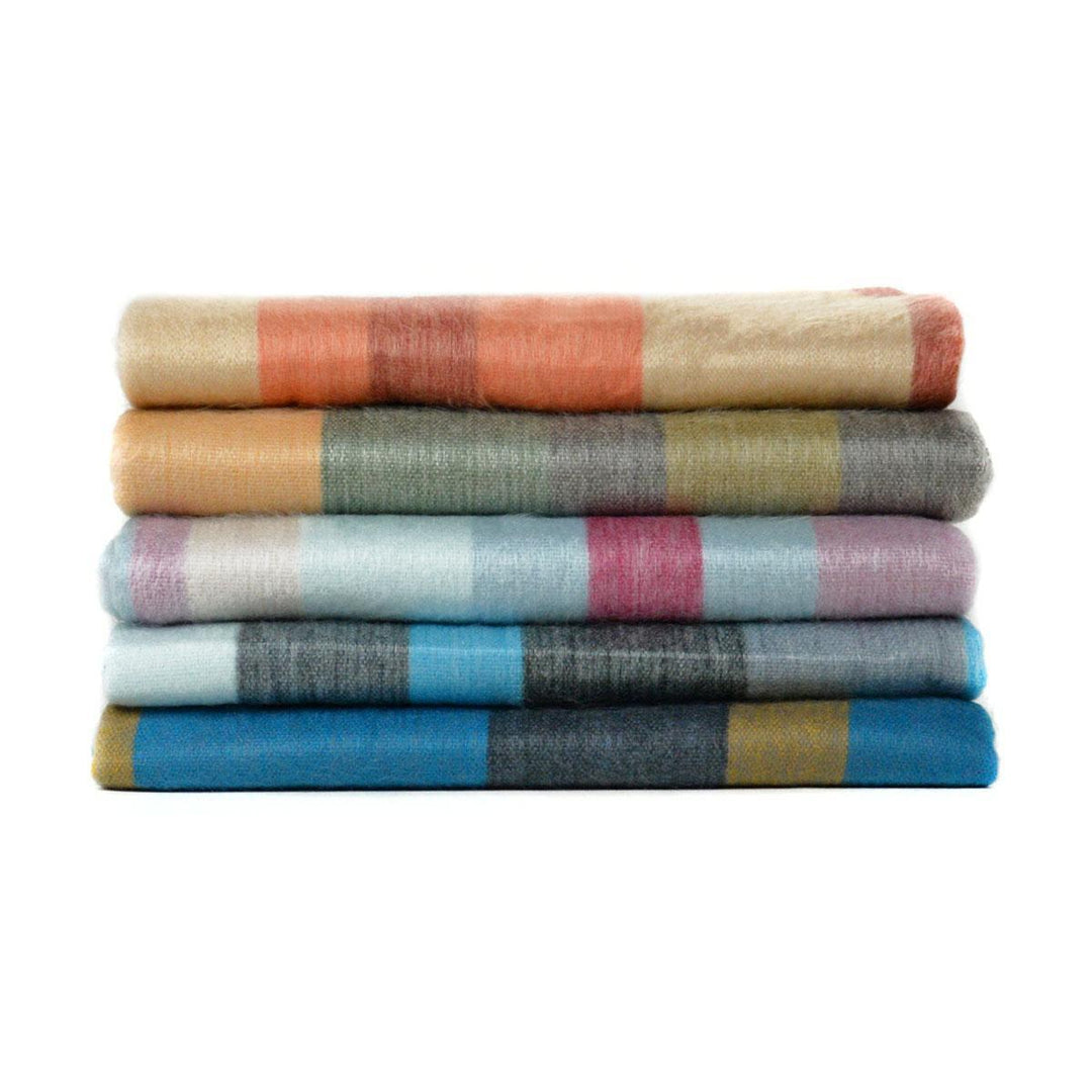 A stack of folded brushed acrylic blankets in various colors, including orange, blue, gray, and multicolored patterns.