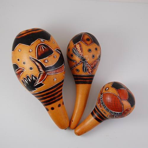 A set of two carved gourd maracas with geometric and animal patterns in orange, brown, and black colors.