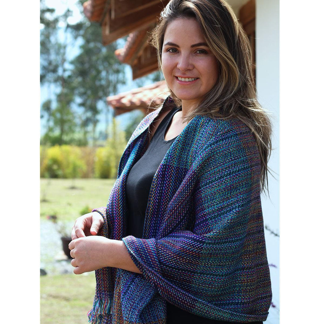 A smiling woman wearing a multicolored geometric patterned shawl.