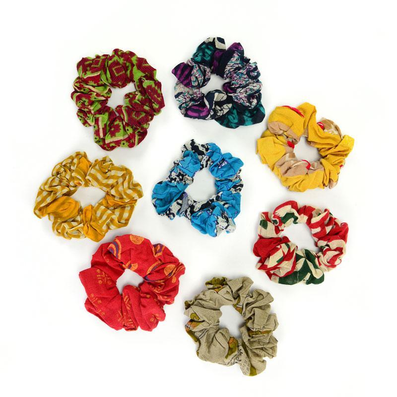 A collection of multicolored cotton sari scrunchies arranged in a circle on a white background.