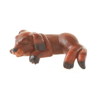 A wooden shelf sitter in the shape of a sleeping dog with black accents on its paws and nose.