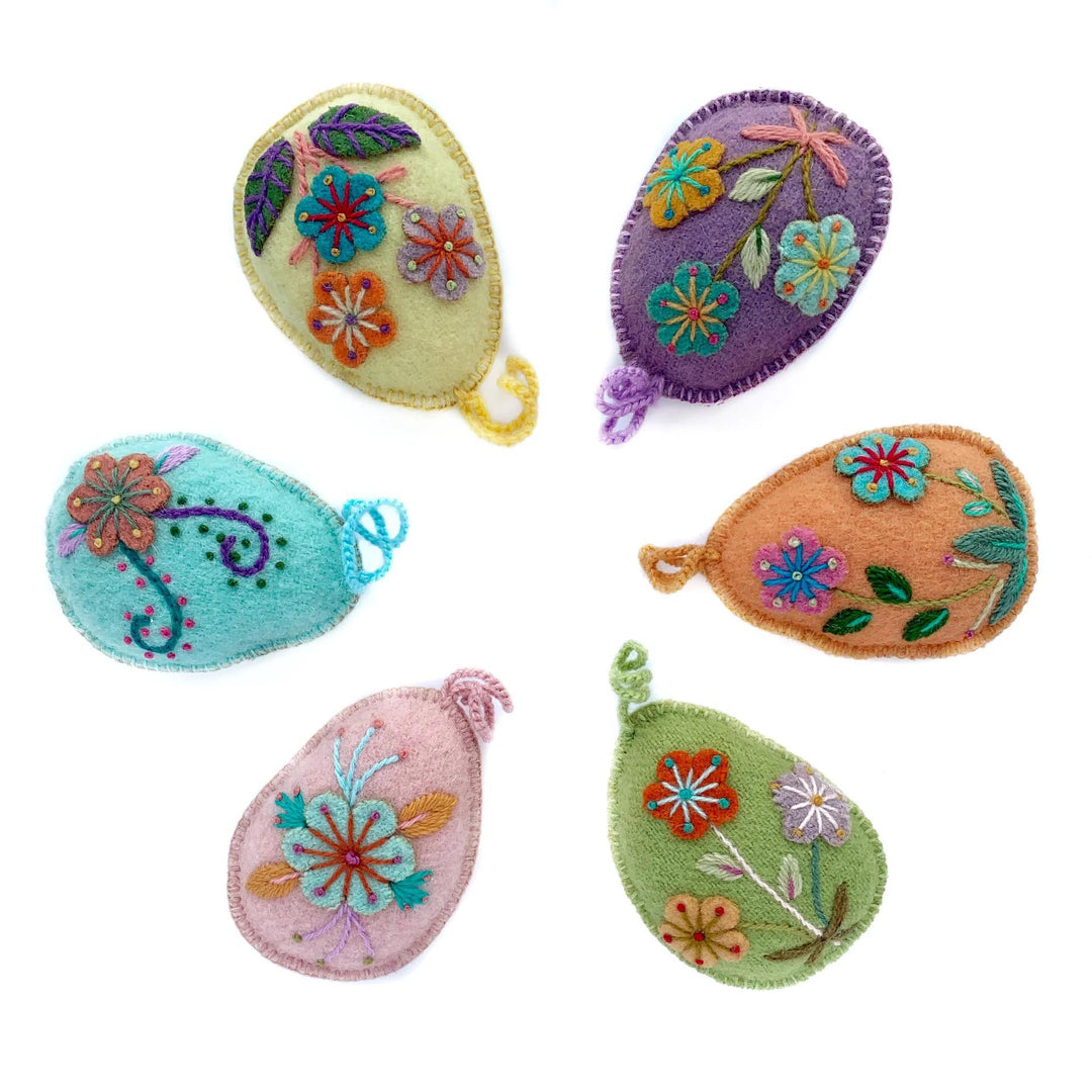 A set of handmade Easter egg ornaments with colorful floral designs, sheep wool, and yarn.