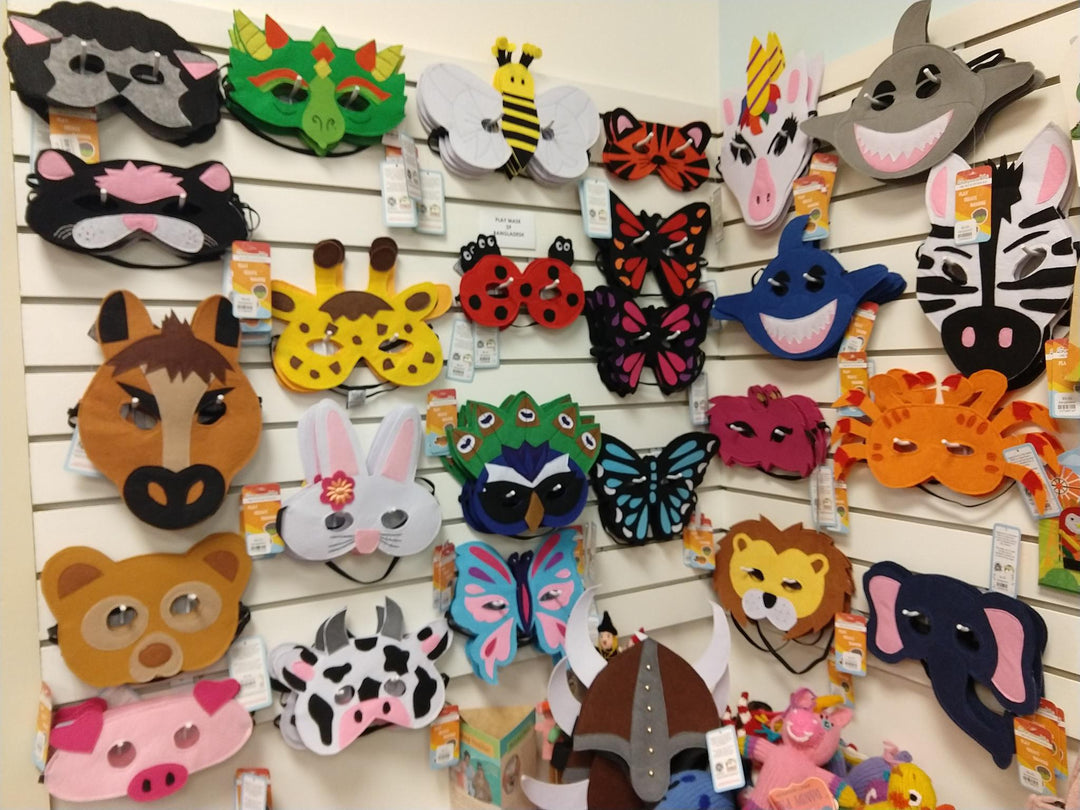A collection of colorful felt play masks displayed on a wall, including animal masks such as a frog, bee, and lion.