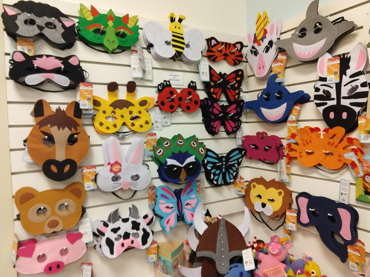 A collection of colorful felt play masks displayed on a wall, including animal masks such as a frog, bee, and lion.