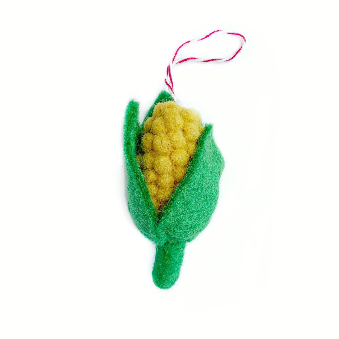 A handmade felt wool ornament in the shape of a corn cob with a green body and a red hanging ribbon.