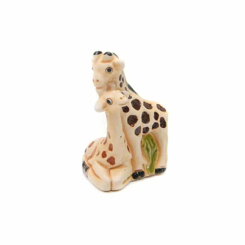 Two ceramic giraffes hugging on a white background. 
