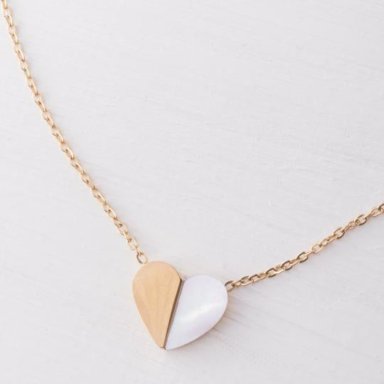 A gold-plated necklace with a heart-shaped pendant, the pendant is split into two, with mother of pearl) and the other half gold. The necklace is shown against a neutral background.