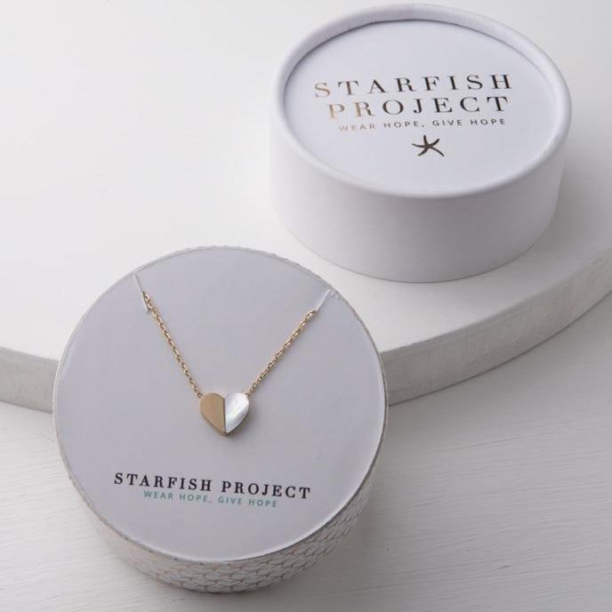 A gold and mother of pearl heart necklace in a Starfish Project box
