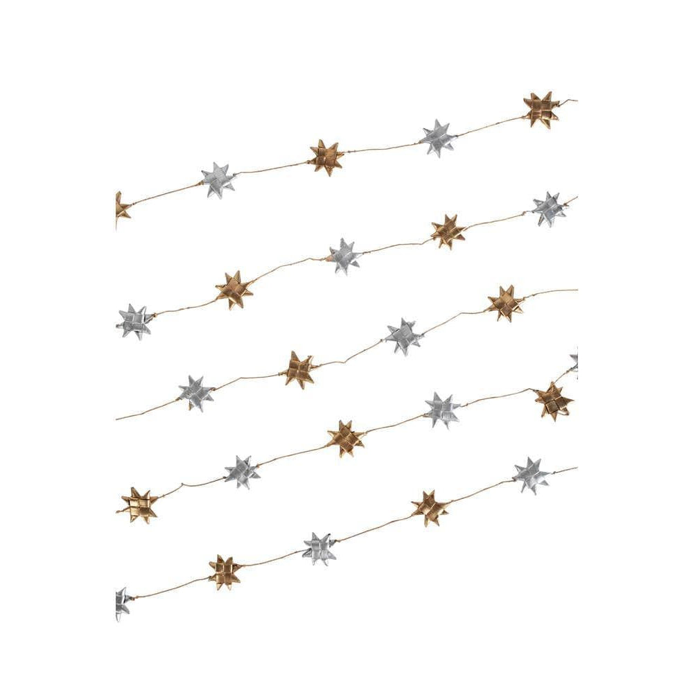A garland made of silver and gold stars strung on a cotton string, laid out against a white background.