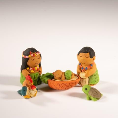 A Hawaiian ceramic nativity set featuring figures of a mother and child, a turtle, a rooster, and a pineapple, all in green and brown colors.