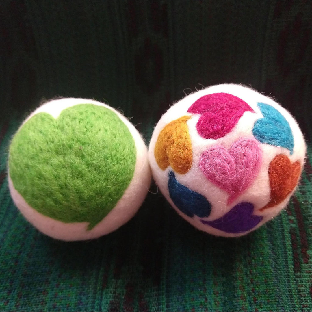 two heart dryer balls on a green knit background
