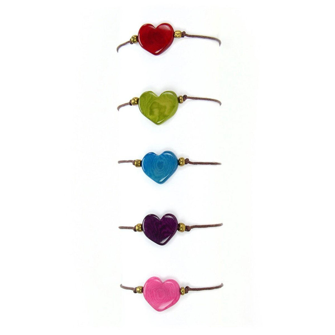 A collection of heart-shaped tagua nut bracelets in various colors, with brass colored beads and wax cording.