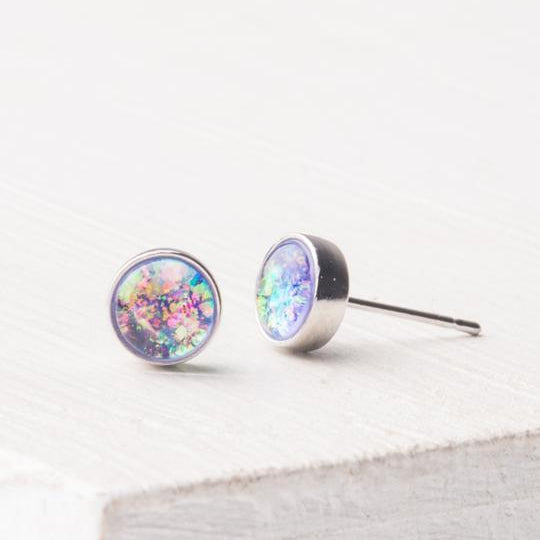 A pair of lavender and silver stud earrings with a sparkling opal design, displayed against a neutral background.