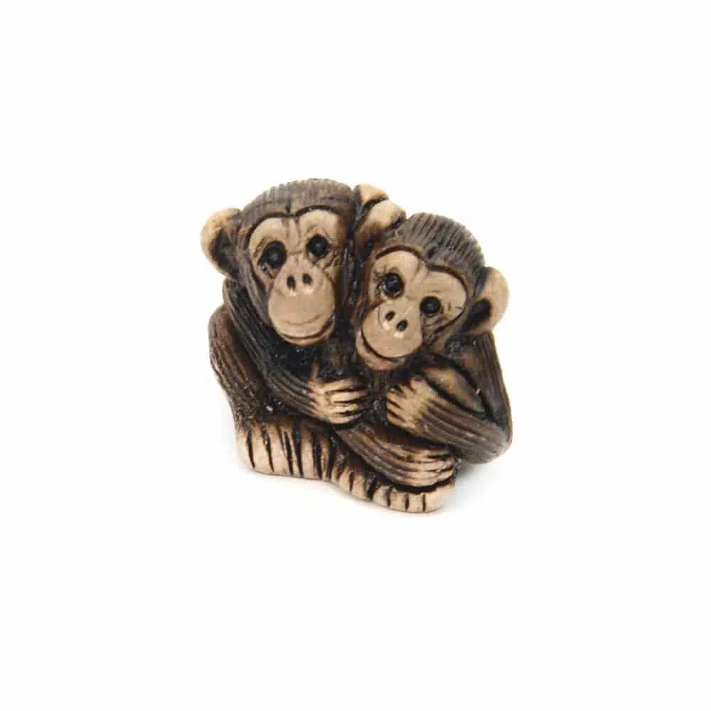 Two monkey ceramic figurines hugging on a white background.