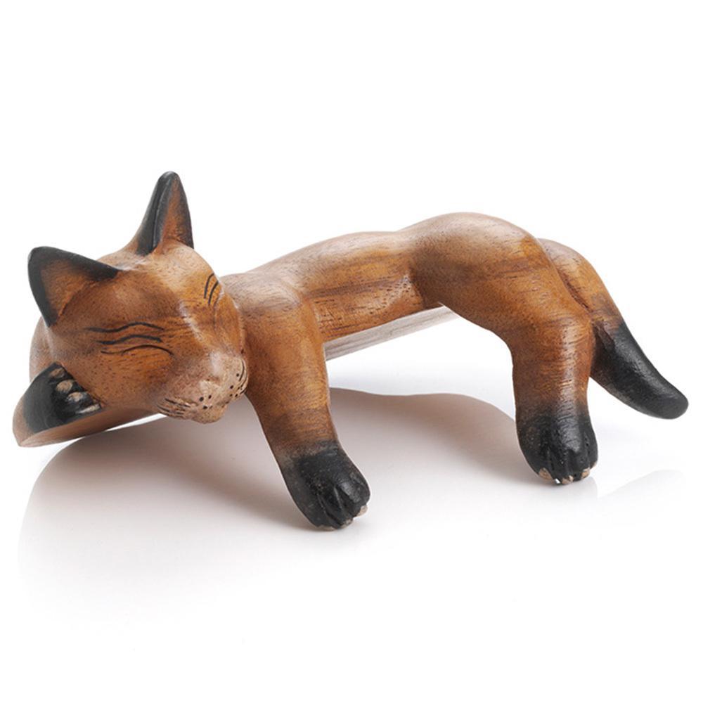 Hand-carved wooden figurine of a sleeping cat with black paint details on paws and face.